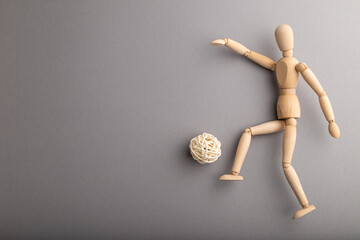 Wooden mannequin playing football on gray pastel background. copy space.