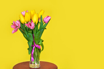 Spring flowers, bouquet of pink tulips on yellow background copy space.