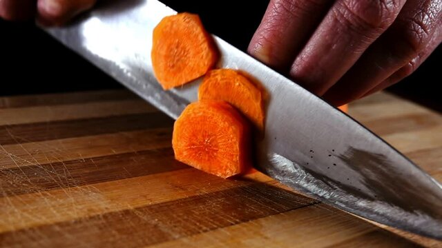 Cutting a carrot with a knife on the chopping board, SLOW MOTION