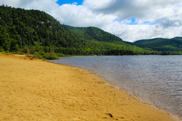 Beautiful sand beach along water shoreline surrounded by green green mountains