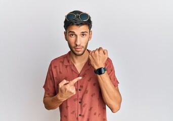 Young handsome man wearing casual summer clothes in hurry pointing to watch time, impatience,...