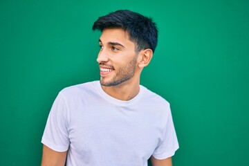 Young latin man smiling happy leaning on the wall at the city.