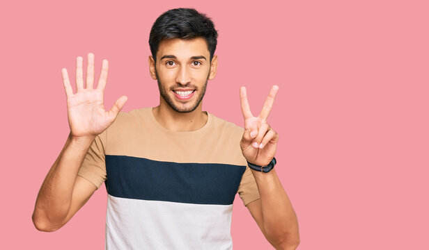 Young handsome man wearing casual clothes showing and pointing up with fingers number seven while smiling confident and happy.