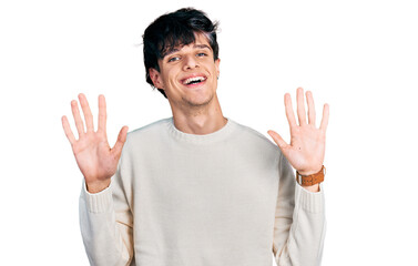 Handsome hipster young man wearing casual winter sweater showing and pointing up with fingers number ten while smiling confident and happy.