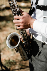 Fototapeta premium handsome young guy plays the saxophone at a gala event on the street. musical accompaniment at the wedding. great musician.