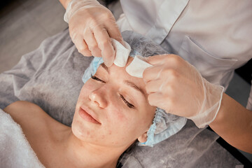A female cosmetologist removes acne with her fingers on the client's face. Professional beauty...