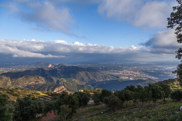 Aerial view of the Montserrat mountains on a beautiful spring day, Catalonia, Spain. Dramatic sky over the mountains. Sunlight falls through the clouds on the ground and mountains.