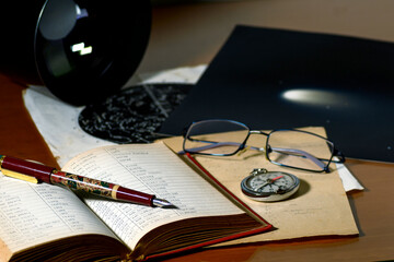 Red book with astronomy notes, glasses, a compass, a celestial map, a photograph of a comet and a large photographic lens