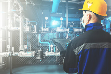 Male engineer in protective helmet, mask and gloves due to coronavirus, with touch controller in...