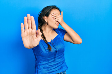 Young hispanic girl wearing casual clothes covering eyes with hands and doing stop gesture with sad and fear expression. embarrassed and negative concept.