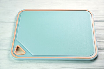 New plastic cutting board on white wooden background