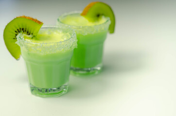 Fruit shot drink based on alcohol, liqueur and cream, decorated with green sugar crystals and a slice of fresh kiwi