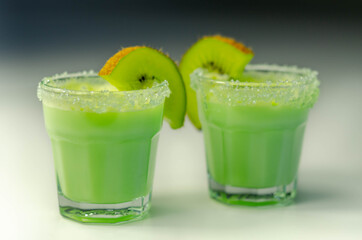 Fruit shot drink based on alcohol, liqueur and cream, decorated with green sugar crystals and a slice of fresh kiwi