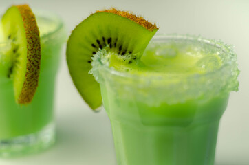 Fruit shot drink based on alcohol, liqueur and cream, decorated with green sugar crystals and a slice of fresh kiwi
