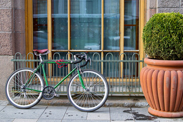Bicycle cyped parked to the fence on the street of the European city by the window 