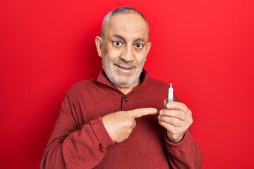 Handsome mature man holding spark plug smiling happy pointing with hand and finger