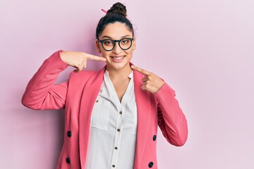 Beautiful middle eastern woman wearing business jacket and glasses smiling cheerful showing and pointing with fingers teeth and mouth. dental health concept.