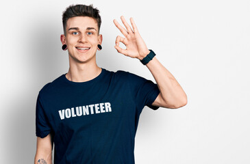 Young caucasian boy with ears dilation wearing volunteer t shirt smiling positive doing ok sign...
