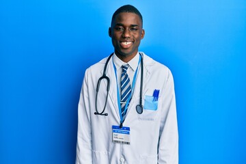 Young african american man wearing doctor uniform with a happy and cool smile on face. lucky person.