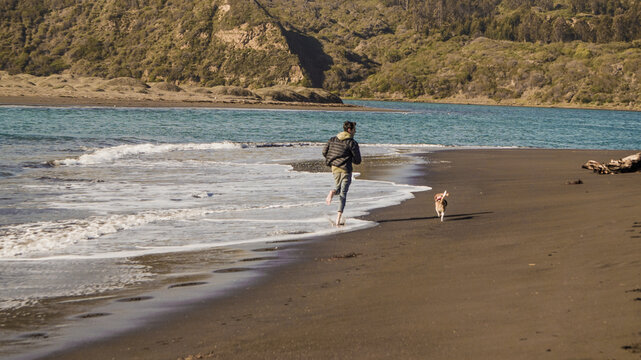 Joven corriendo en playa invierno y perrita beagle 4