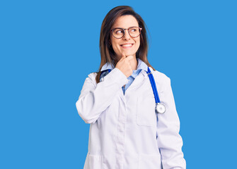 Young beautiful woman wearing doctor stethoscope and glasses with hand on chin thinking about question, pensive expression. smiling with thoughtful face. doubt concept.