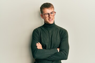 Young caucasian man wearing glasses with arms crossed gesture winking looking at the camera with...