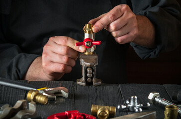 Plumber connects brass fittings while repairing equipment. Close up of the hand of the master during work in workshop