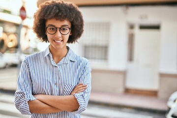 Obraz premium Young hispanic businesswoman with arms crossed smiling happy at the city.