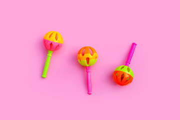 Colorful baby rattles on pink background.
