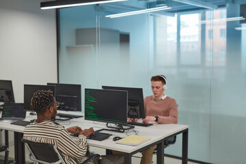 Background image of IT programmers or students using computers in office interior with glass wall, copy space