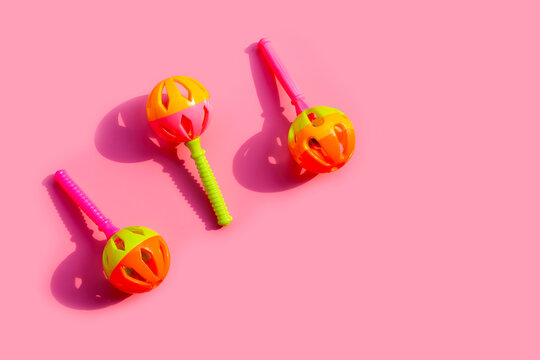 Colorful baby rattles on pink background. Copy space © Bowonpat