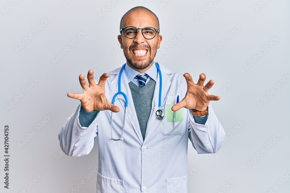 Canvas Prints Hispanic adult man wearing doctor uniform and stethoscope smiling funny doing claw gesture as cat, aggressive and sexy expression