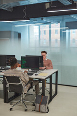 Vertical full length of IT programmers or students using computers in office interior with glass wall, copy space