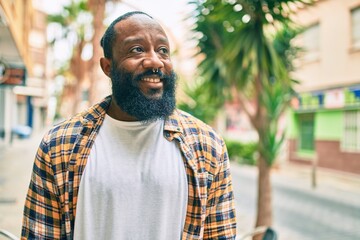 Handsome modern african american man with beard smiling positive standing at the street