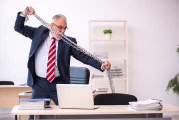Old businessman employee holding chain in the office