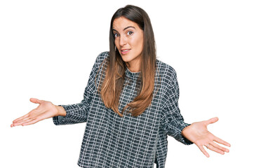 Young beautiful woman wearing casual clothes clueless and confused expression with arms and hands...