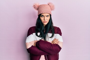 Young hispanic woman wearing wool winter sweater and cap skeptic and nervous, disapproving...