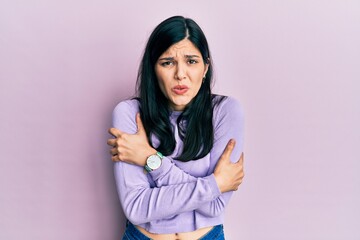 Fototapeta premium Young hispanic woman wearing casual clothes shaking and freezing for winter cold with sad and shock expression on face