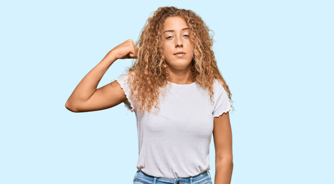 Beautiful caucasian teenager girl wearing casual white tshirt strong person showing arm muscle, confident and proud of power