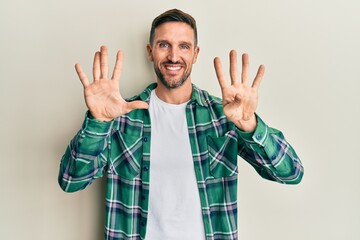 Handsome man with beard wearing casual clothes showing and pointing up with fingers number nine...