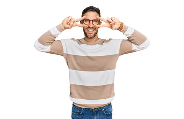 Fototapeta premium Handsome man with beard wearing casual clothes and glasses doing peace symbol with fingers over face, smiling cheerful showing victory
