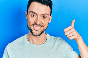 Young hispanic man wearing casual clothes smiling happy and positive, thumb up doing excellent and approval sign