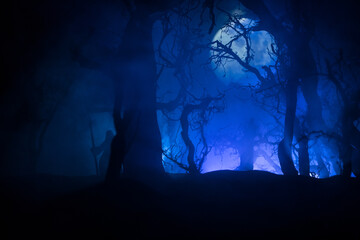 Death with a scythe in the dark misty forest. Woman horror ghost holding reaper in forest, halloween concept