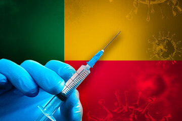 Benin Covid-19 Vaccination Campaign. Hand in a blue rubber glove holds a syringe with covid-19 virus vaccine in front of Benin flag