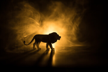 A silhouette of lion miniature standing on wooden table. Creative decoration with colorful backlight with fog. Selective focus © zef art