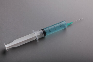 Syringe on a gray background. Cosmetology and medicine. Coronavirus vaccine concept. Flat lay.