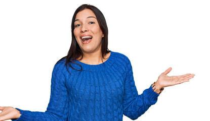 Young hispanic woman wearing casual clothes clueless and confused expression with arms and hands...