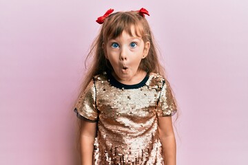 Little caucasian girl kid wearing festive sequins dress afraid and shocked with surprise...