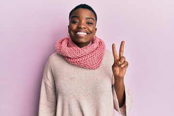 Young african american woman wearing winter scarf smiling with happy face winking at the camera...