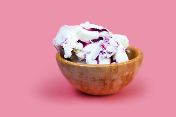 Creamy ice cream with berry syrup. Ice cream in wooden bowl isolated on pink background. Food background concept